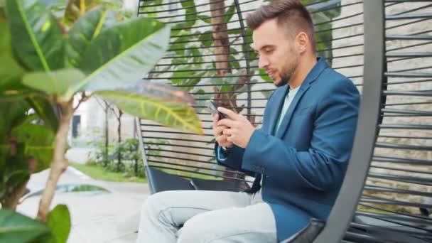 Joven empresario caucásico exitoso trabaja en un salón con una computadora. Negocios, freelance y trabajo remoto. — Vídeos de Stock