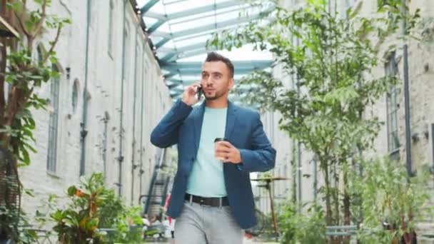 Un joven empresario exitoso está caminando por la calle. Un hombre con ropa casual. Negocios, freelance y trabajo remoto. — Vídeos de Stock