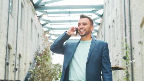 Un joven empresario exitoso está trabajando al aire libre con un teléfono inteligente. Un hombre con ropa casual. Negocios, freelance y trabajo remoto. — Vídeos de Stock