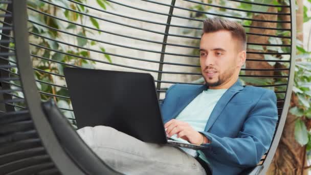 Joven empresario caucásico exitoso trabaja en un salón con una computadora. Negocios, freelance y trabajo remoto. — Vídeos de Stock