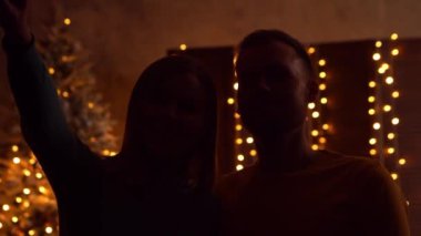 Genç bir çift Noel 'i evde kutluyor ve pencereden havai fişekleri izliyor. Genç adam ve kız arkadaşı arka planda Noel ağacı olan bir evde..