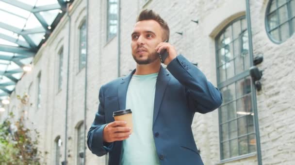 Un joven empresario exitoso está trabajando al aire libre con un teléfono inteligente. Un hombre con ropa casual. Negocios, freelance y trabajo remoto. — Vídeos de Stock