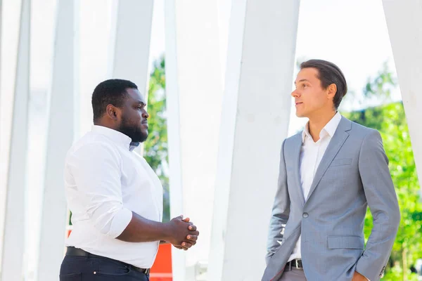 非裔美国商人和他的同事在现代办公大楼前。金融投资者在室外谈论。银行和商业概念. — 图库照片