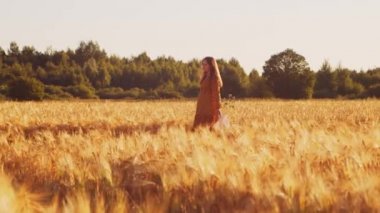 Günbatımında hamile bir kadın. Güzel bir genç kız bir çocuğun doğmasını umarak tarlada yürüyor. Annelik ve hamilelik kavramı.