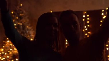 Genç bir çift Noel 'i evde kutluyor ve pencereden havai fişekleri izliyor. Genç adam ve kız arkadaşı arka planda Noel ağacı olan bir evde..