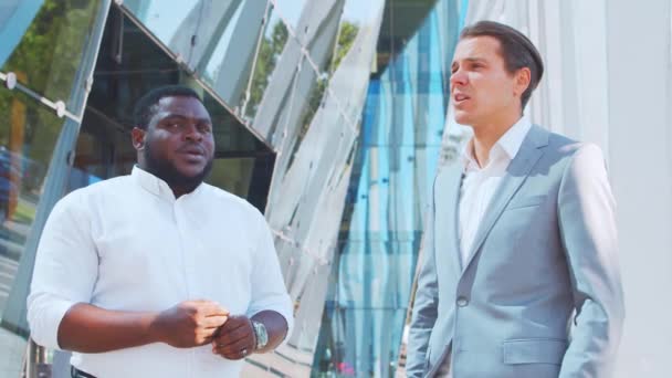 Homme d'affaires afro-américain confiant et son collègue devant un immeuble de bureaux moderne. Les investisseurs financiers parlent en plein air. Banques et entreprises. — Video