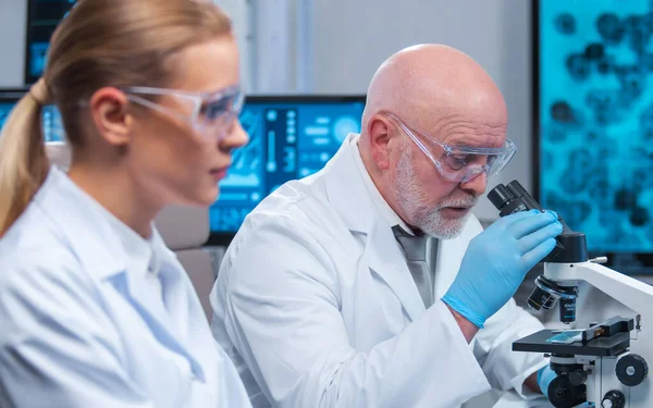 Professor och läkare arbetar i ett modernt vetenskapligt laboratorium med hjälp av utrustning och datateknik. Forskargruppen gör forskning och utvecklar nya vacciner. Vetenskap och hälsovård. — Stockfoto