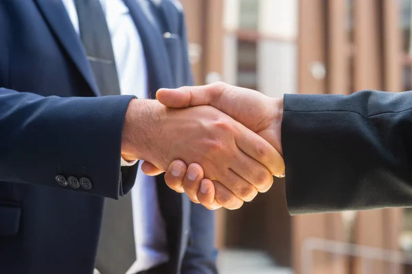 Stringi la mano. L'uomo d'affari e il suo collega si stanno stringendo la mano davanti a un moderno edificio per uffici. Investitori finanziari all'aperto. Settore bancario e commerciale. — Foto Stock