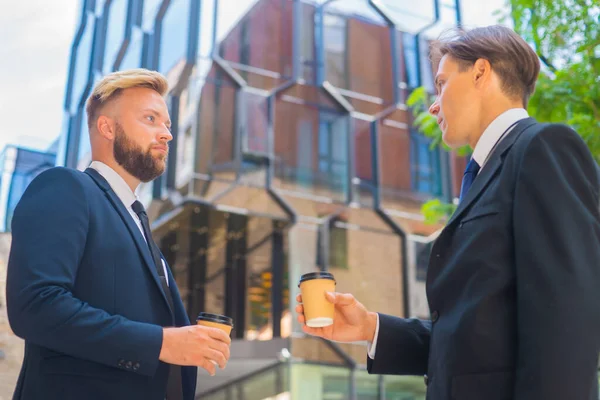 Zelfverzekerde zakenman en zijn collega tegenover modern kantoorgebouw. Financiële investeerders hebben het over buitenshuis. Bankieren en bedrijfsleven. — Stockfoto