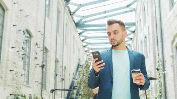 Ένας νεαρός επιτυχημένος επιχειρηματίας εργάζεται σε εξωτερικούς χώρους χρησιμοποιώντας smartphone. Ένας άντρας με ένα απλό ντύσιμο. Επαγγελματική, ανεξάρτητη και εξ αποστάσεως εργασία. — Αρχείο Βίντεο