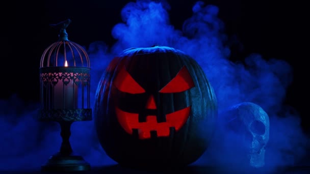 Scary laughing pumpkin and an old skull on a dark background. Halloween, witchcraft and magic. — Stock Video