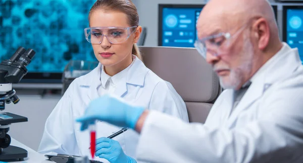 Profesor y doctor trabajan en un moderno laboratorio científico utilizando equipos y tecnologías informáticas. Un grupo de científicos investiga y desarrolla nuevas vacunas. Concepto de ciencia y salud. —  Fotos de Stock