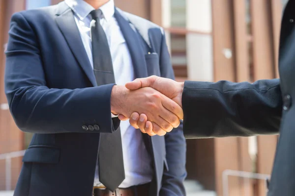 Stringi la mano. L'uomo d'affari e il suo collega si stanno stringendo la mano davanti a un moderno edificio per uffici. Investitori finanziari all'aperto. Settore bancario e commerciale. — Foto Stock