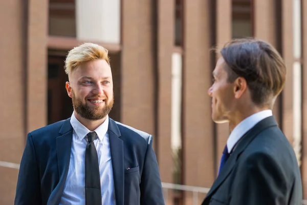 Modern ofis binasının önünde kendinden emin bir iş adamı ve meslektaşı. Finansal yatırımcılar dışarıda konuşuyorlar. Bankacılık ve iş. Stok Fotoğraf