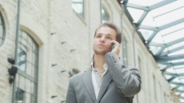 Un joven empresario exitoso está trabajando al aire libre con un teléfono inteligente. Un hombre con ropa casual. Negocios, freelance y trabajo remoto. — Vídeos de Stock