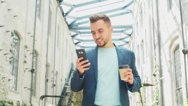 Ένας νεαρός επιτυχημένος επιχειρηματίας εργάζεται σε εξωτερικούς χώρους χρησιμοποιώντας smartphone. Ένας άντρας με ένα απλό ντύσιμο. Επαγγελματική, ανεξάρτητη και εξ αποστάσεως εργασία. — Αρχείο Βίντεο
