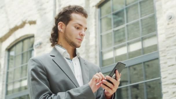 Mladý úspěšný podnikatel pracuje venku pomocí chytrého telefonu. Muž v neformálním oblečení. Práce na volné noze a na dálku. — Stock video