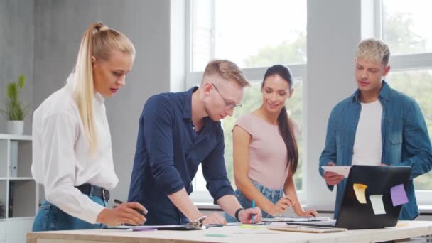 Het team van jonge startupers werkt aan de tafel in het kantoor en bespreekt de strategie en het ontwikkelingsplan van het bedrijf. Bedrijfs-, innovatie-, brainstorm- en teamwerkconcept. — Stockvideo