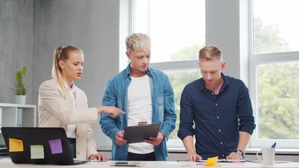 Une équipe de jeunes startupers travaille à la table du bureau, discutant de la stratégie et du plan de développement de l'entreprise. Concept d'entreprise, d'innovation, de réflexion et de travail d'équipe. — Video