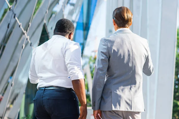 Der afroamerikanische Geschäftsmann und sein Kollege vor einem modernen Bürogebäude. Finanzinvestoren reden im Freien. Bank- und Geschäftskonzept. — Stockfoto