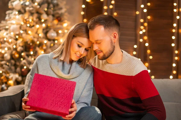 Jeune couple amoureux célébrant Noël à la maison. Jeune homme et sa jolie petite amie dans un intérieur de maison avec un arbre de Noël. — Photo