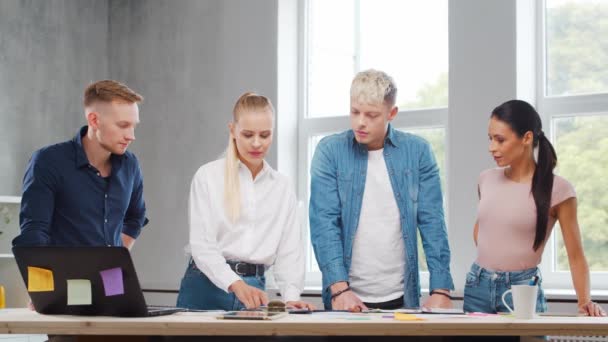 Une équipe de jeunes startupers travaille à la table du bureau, discutant de la stratégie et du plan de développement de l'entreprise. Concept d'entreprise, d'innovation, de réflexion et de travail d'équipe. — Video