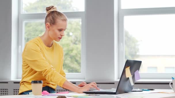 Szabadúszó munkás vagy diáklány munkahelye az otthoni irodában. A fiatal nő számítógéppel és más eszközökkel dolgozik. Távmunka-koncepció. — Stock videók