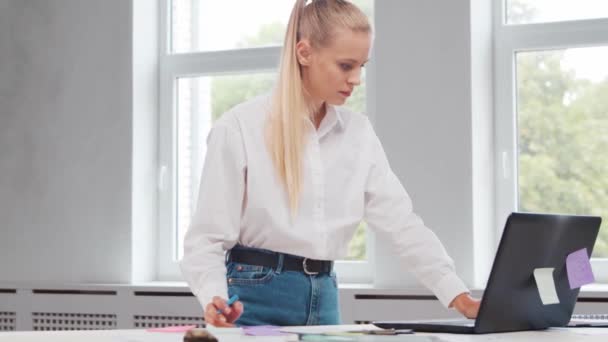 프리랜서 직원의 직장 또는 가정 사무실의 여학생. 젊은 여자는 컴퓨터와 그 밖의 장치를 사용하여 일합니다. 원격 직업 개념. — 비디오
