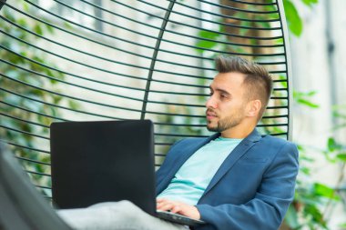 Genç başarılı beyaz iş adamı bir salonda bilgisayar kullanarak çalışıyor. İş, serbest meslek ve uzak çalışma.