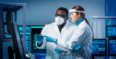 Bir grup mikro elektronik mühendisi modern bir mikroişlemci laboratuvarında tartışıyorlar. Elektronik tasarımcıların işyeri. Yenilikler ve icatlar kavramı.