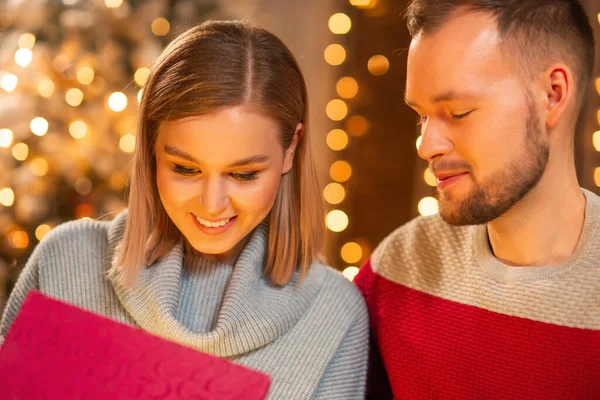 Young loving couple celebrating Christmas at home. Young man and his attractive girlfriend in a home interior with a Christmas tree. — Stock Photo, Image