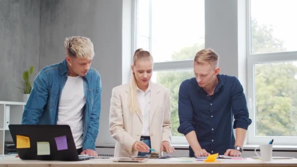 El equipo de jóvenes startups está trabajando en la mesa de la oficina, discutiendo la estrategia y el plan de desarrollo de la empresa. Negocios, innovación, lluvia de ideas y trabajo en equipo. — Vídeos de Stock