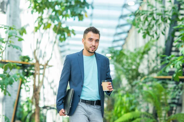 Een jonge succesvolle zakenman loopt door de straat. Een man in casual kleding. Bedrijven, freelance en werk op afstand. — Stockfoto