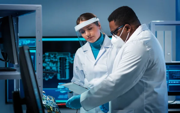 Bir grup mikro elektronik mühendisi modern bir mikroişlemci laboratuvarında tartışıyorlar. Elektronik tasarımcıların işyeri. Yenilikler ve icatlar kavramı.