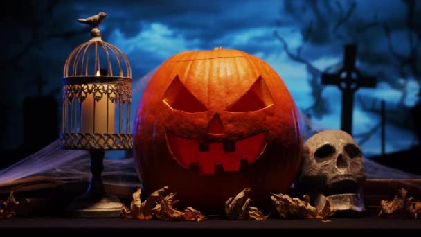 Enge lachende pompoen en een oude schedel over de angstaanjagende gotische begraafplaats achtergrond. Halloween, hekserij en magie. — Stockvideo