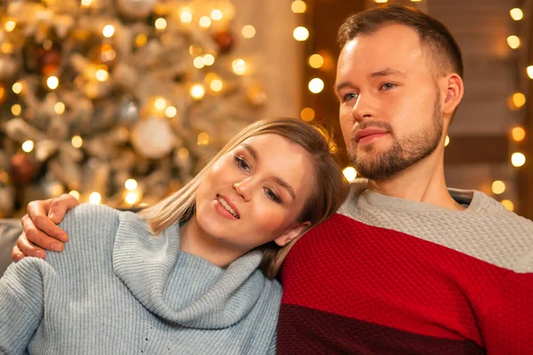 Young loving couple celebrating Christmas at home. Young man and his attractive girlfriend in a home interior with a Christmas tree. — Stock Photo, Image