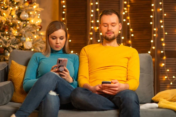 Jeune couple amoureux célébrant Noël à la maison. Jeune homme et sa jolie petite amie dans un intérieur de maison avec un arbre de Noël. — Photo