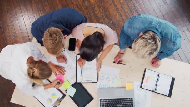 Une équipe de jeunes startupers travaille à la table du bureau, discutant de la stratégie et du plan de développement de l'entreprise. Concept d'entreprise, d'innovation, de réflexion et de travail d'équipe. — Video