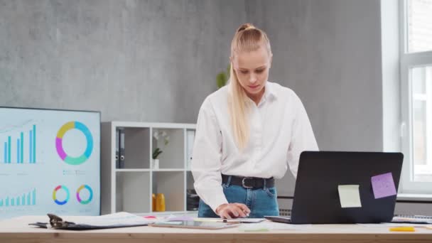 Lugar de trabajo del trabajador independiente o de una estudiante en la oficina del hogar. Mujer joven trabaja usando la computadora y otros dispositivos. Concepto de trabajo remoto. — Vídeos de Stock