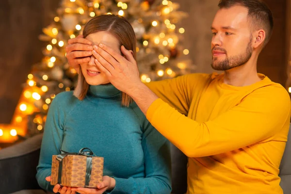 Jeune couple amoureux célébrant Noël à la maison. Jeune homme et sa jolie petite amie dans un intérieur de maison avec un arbre de Noël. — Photo