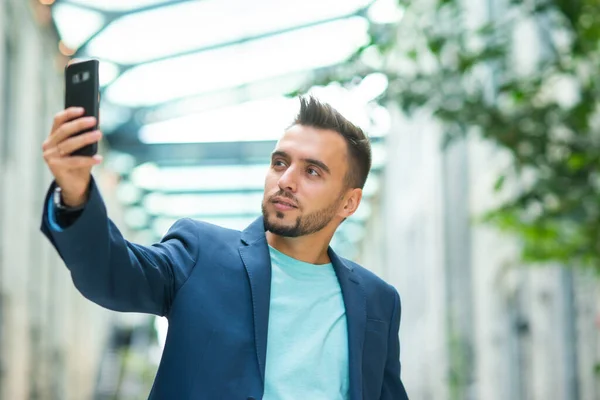 Un giovane uomo d'affari di successo sta lavorando all'aperto utilizzando lo smartphone. Uomo con un abbigliamento casual. Affari, freelance e lavoro a distanza. — Foto Stock