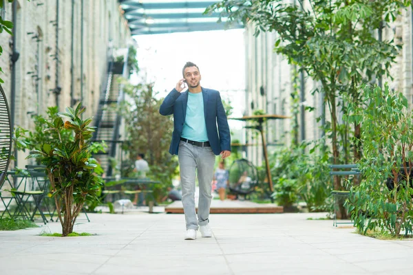 A young successful businessman is working outdoor using smartphone. Man in a casual wear. Business, freelance and remote work. — Stock Photo, Image