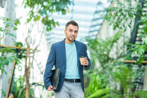 Un joven empresario exitoso está caminando por la calle. Un hombre con ropa casual. Negocios, freelance y trabajo remoto. —  Fotos de Stock