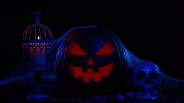 Enge lachende pompoen en een oude schedel op een donkere achtergrond. Halloween, hekserij en magie. — Stockvideo