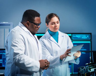 Bir grup mikro elektronik mühendisi modern bir mikroişlemci laboratuvarında tartışıyorlar. Elektronik tasarımcıların işyeri. Gelecekteki yenilikler ve geleceğin icatları kavramı..