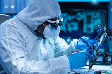 Afrikalı-Amerikalı bilim adamı, mikro elektronik ve işlemcilerin araştırılması ve geliştirilmesi için modern bir bilim laboratuvarında çalışıyor. Üretim işçisi bilgisayar teknolojisi ve ekipmanı kullanıyor.