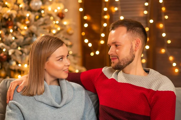Pareja joven y cariñosa celebrando la Navidad en casa. Joven y su atractiva novia en el interior de una casa con un árbol de Navidad. — Foto de Stock