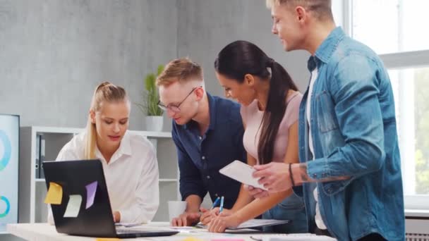 Une équipe de jeunes startupers travaille à la table du bureau, discutant de la stratégie et du plan de développement de l'entreprise. Concept d'entreprise, d'innovation, de réflexion et de travail d'équipe. — Video