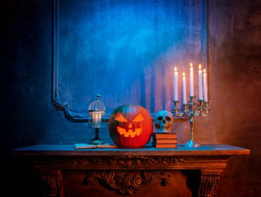 Korkunç gülen balkabağı ve eski kafatası antik gotik şöminede. Cadılar Bayramı, büyücülük ve sihir.