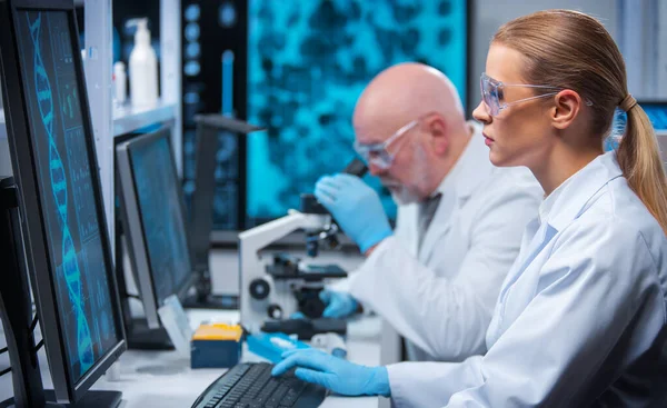 Profesor y doctor trabajan en un moderno laboratorio científico utilizando equipos y tecnologías informáticas. Un grupo de científicos investiga y desarrolla nuevas vacunas. Concepto de ciencia y salud. —  Fotos de Stock